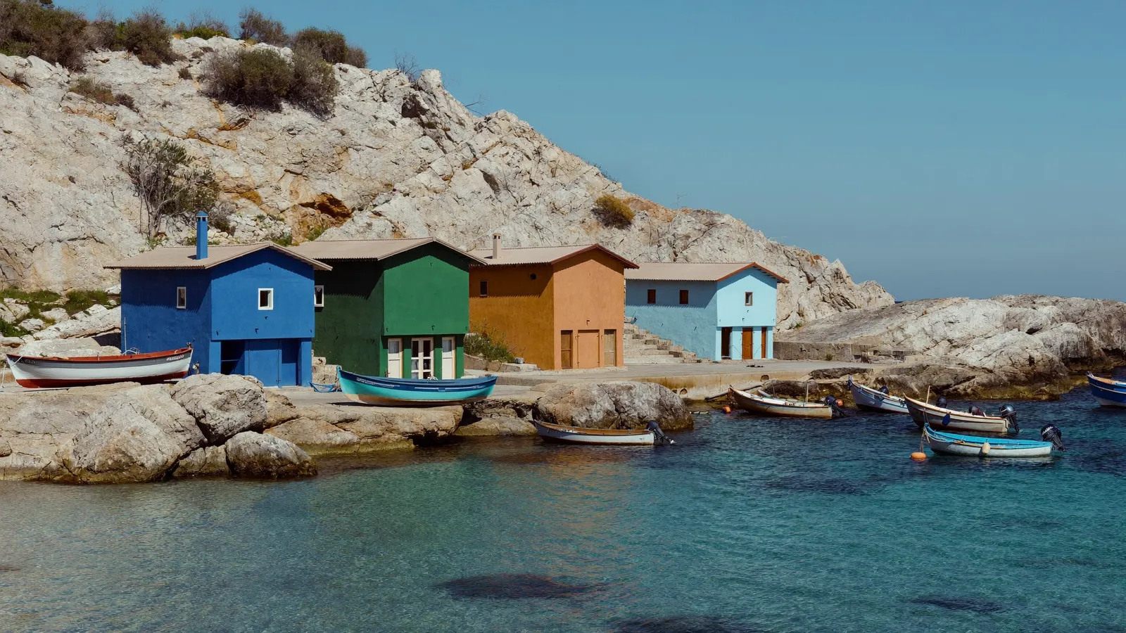 Cabanons colorés de pêcheurs au bord d'une calanque marseillaise, eau turquoise et rochers calcaires